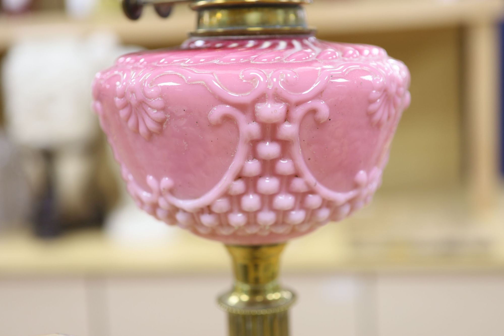 A late Victorian brass oil lamp with pink glass reservoir and a cranberry oil lamp